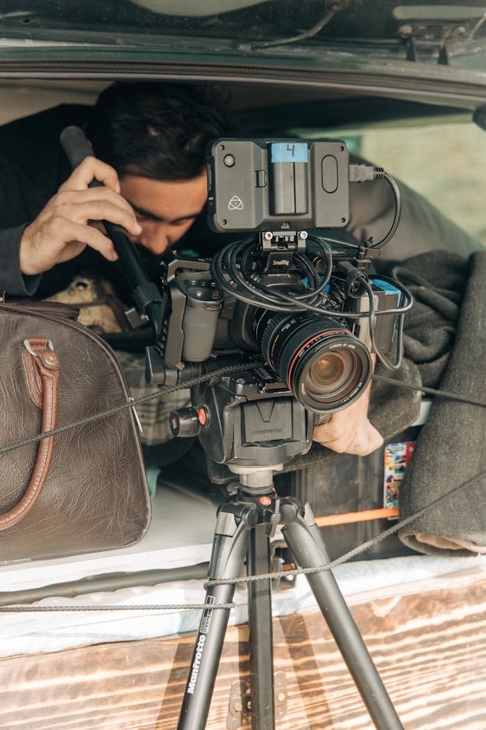 Filmmaker adjusting camera equipment with precision in an outdoor setting.
